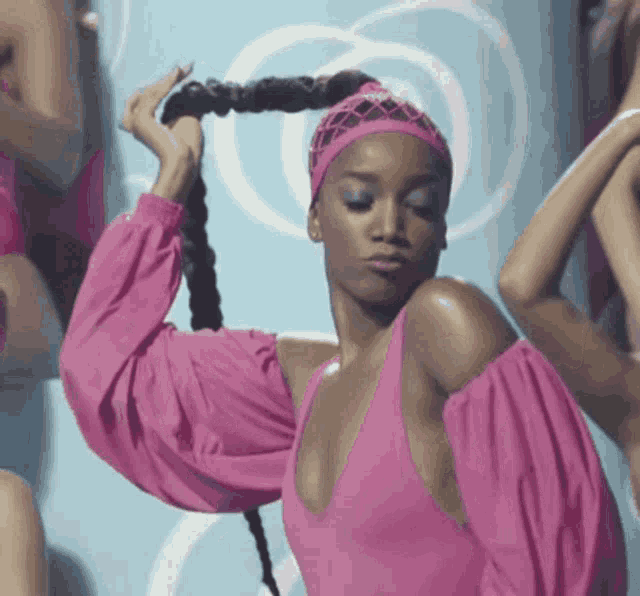 a woman in a pink dress is holding her hair