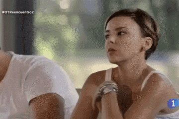 a woman is sitting next to a man in a white shirt and looking at the camera .
