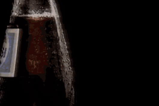 a bottle of pepsi is being poured into a glass .