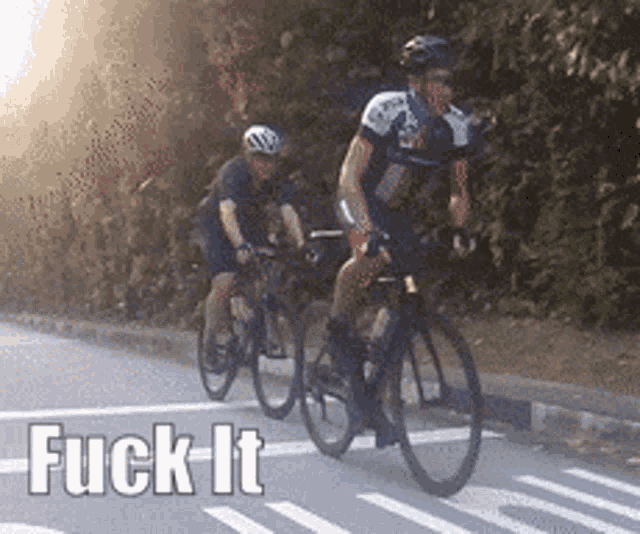 two men are riding bicycles down a street with the words fuck it on the bottom right
