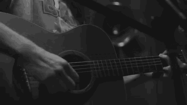 a black and white photo of a man playing a guitar