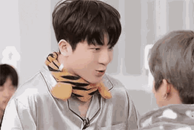 a man wearing a tiger scarf around his neck is standing next to another man .