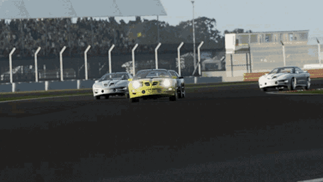 a yellow car with the word triumph on the front is driving down a race track