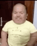 a man with a bald head and a mustache is wearing a yellow shirt and smiling .