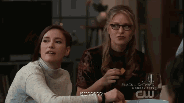 two women sit at a table with a glass of wine and a sign that says black lightning