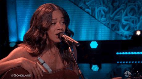 a woman singing into a microphone with #songland written on the bottom right