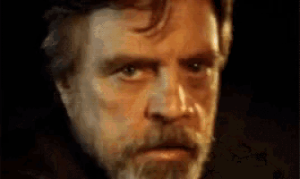 a close up of a man 's face with a beard making a serious face .