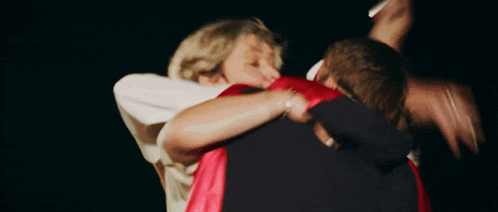 a woman in a white shirt is hugging a man in a black jacket