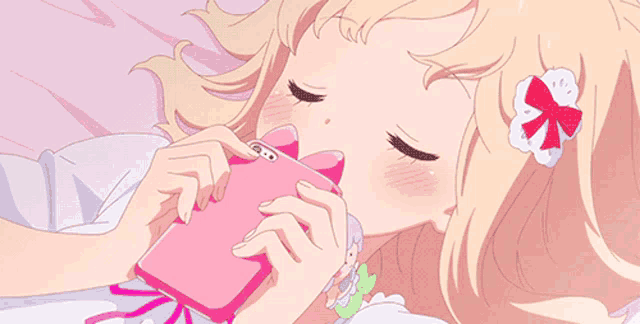 a blonde anime girl is laying on a bed holding a pink cell phone