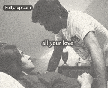 a man is kissing a woman on the forehead while laying in bed .