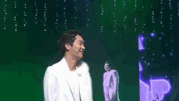 a man in a white shirt is standing on a stage with a green background