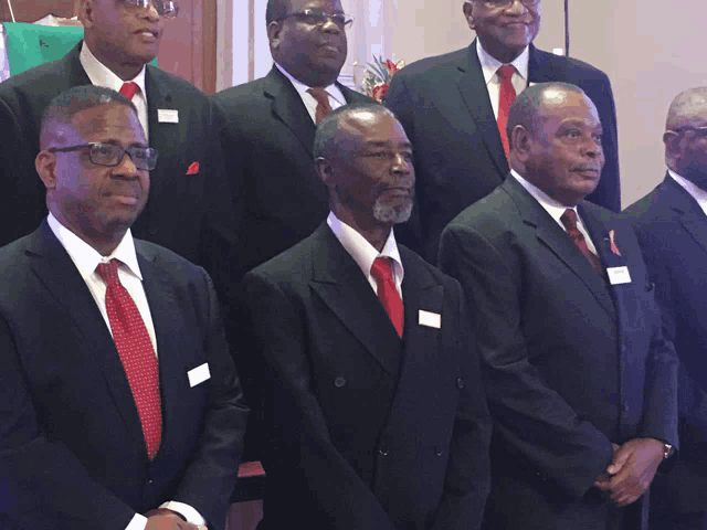 a group of men wearing suits and ties pose for a photo