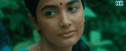 a close up of a woman 's face with a red dot on her forehead and x hk written on the bottom