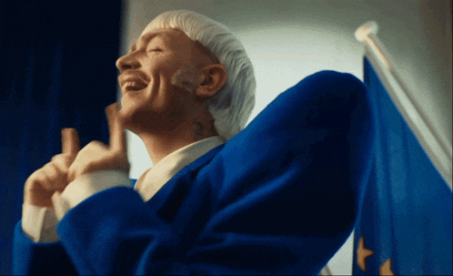 a man in a blue suit is giving a thumbs up sign