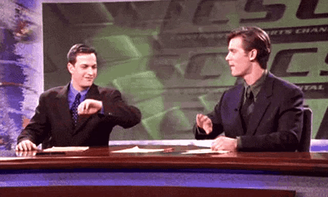 two men are sitting at a desk in front of a sign that says ' usc sports central '