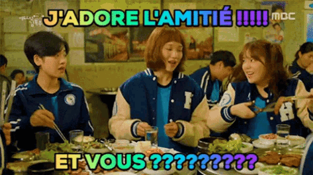 a group of people are sitting at a table with a sign that says j'adore l' amitie !!!