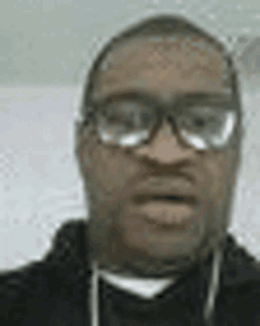 a man wearing glasses and a hoodie is taking a selfie .