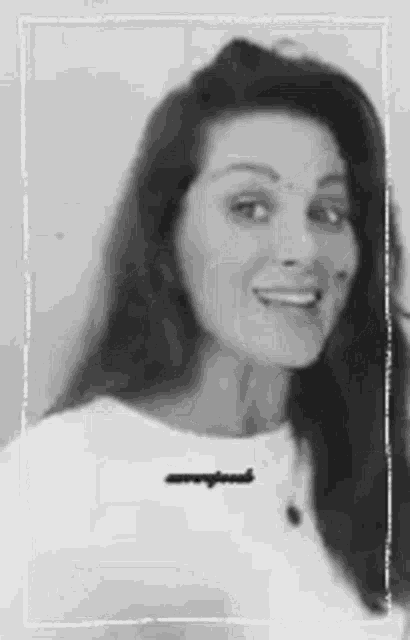 a black and white photo of a woman with long hair and a white shirt .