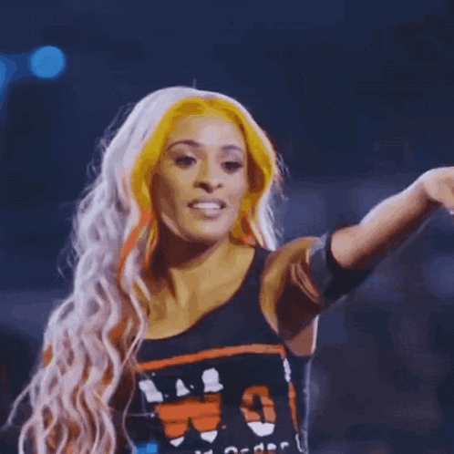 a woman with long blonde hair and orange highlights is blowing a kiss .