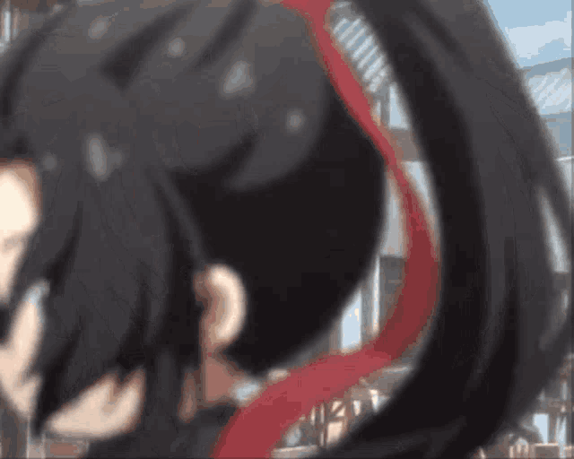 a blurry picture of a person with long black hair and a red ribbon around their neck .