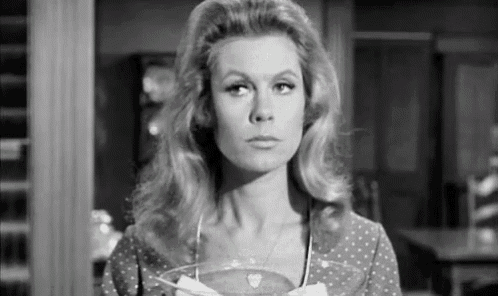 a black and white photo of a woman in a polka dot dress holding a glass bowl .
