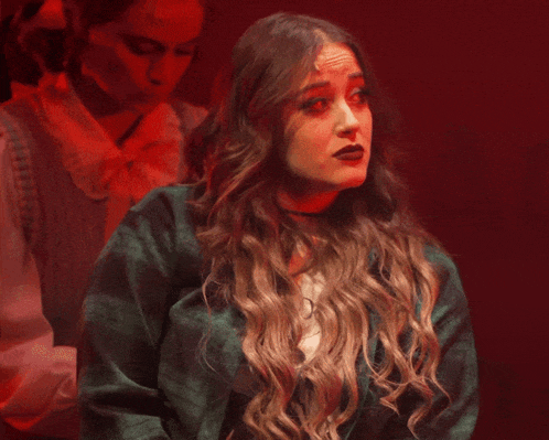 a woman wearing a green plaid jacket and a white shirt with the letter m on the front