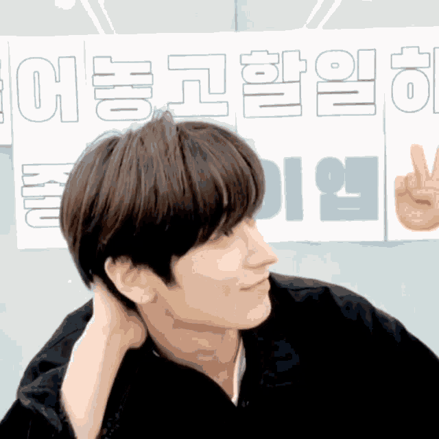 a man adjusts his hair in front of a sign that says ' i 'm sorry '