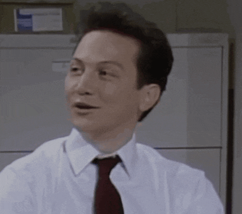 a man in a white shirt and red tie is sitting in an office .