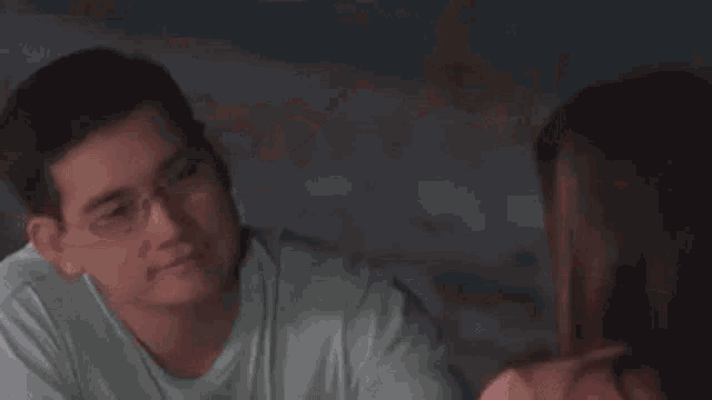 a man and a woman are looking into each other 's eyes . the man is wearing glasses .