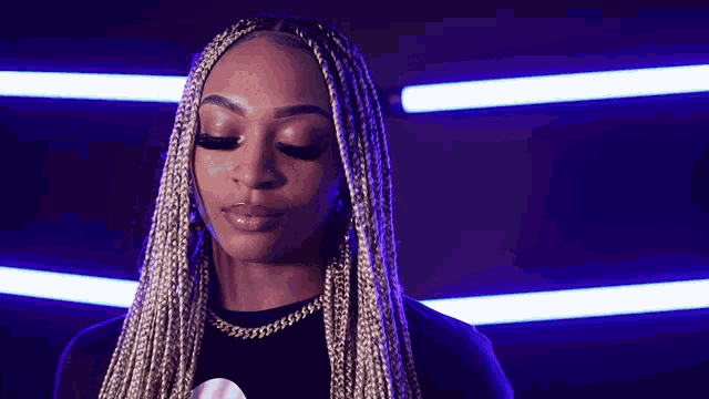a woman with braids is wearing a black shirt and a necklace