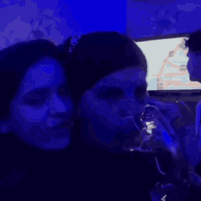 two women are drinking wine in a dark room