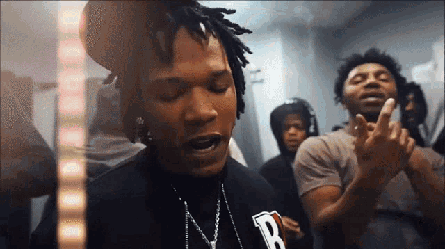 a man with dreadlocks is wearing a black shirt with the letter p on it