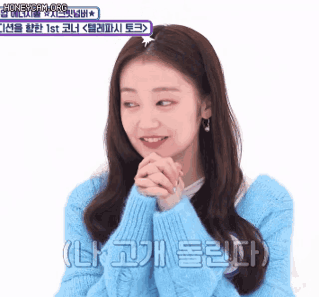 a woman in a blue sweater is smiling with her hands folded