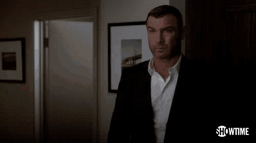 a man in a suit and white shirt is standing in a dark room and says understand