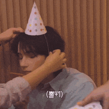 a person is putting a party hat on a boy 's head