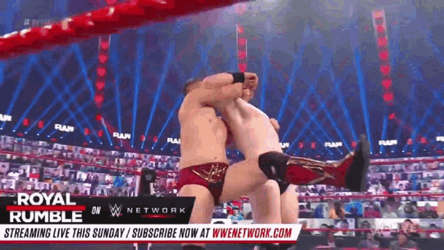 two men are wrestling in a wrestling ring with a banner that says royal rumble on it