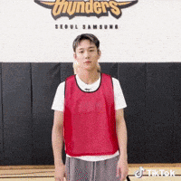 a man wearing a red vest is standing in front of a wall with the word thunders on it