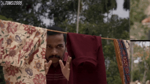 a man peeking out from behind a clothes line with a toms 2005 logo in the background