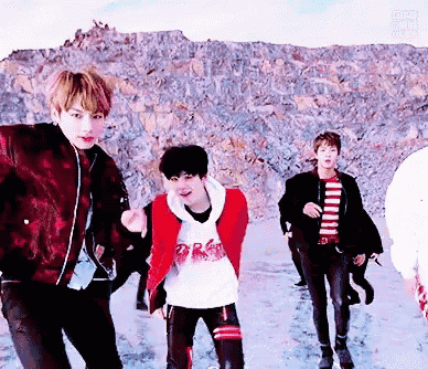 a group of young men are walking in the snow and one of them is wearing a red jacket that says ' army ' on it