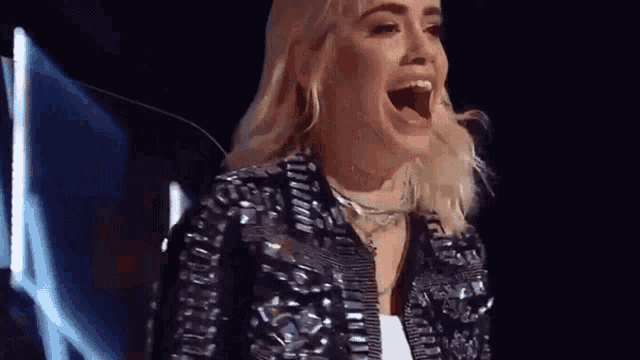 a woman is standing on a stage with her mouth open and screaming .