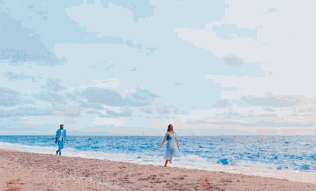 a woman in a blue dress walks along the beach