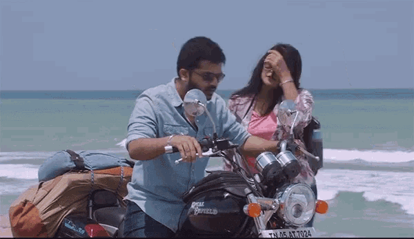 a man is sitting on a royal enfield motorcycle while a woman looks on