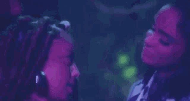 a woman is holding another woman 's neck in a dark room with purple lights .