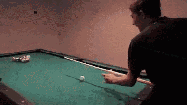 a man is playing pool in a dark room with balls on the table