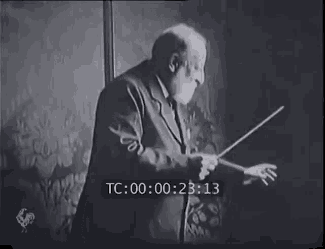 a black and white photo of a man holding a baton with the time tc 00 00 25 21