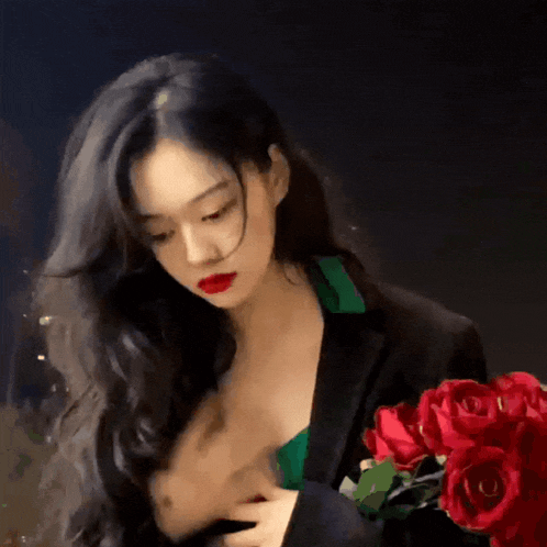 a woman is holding a bouquet of red roses in her hand