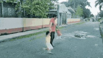 a man is walking down a street with a child