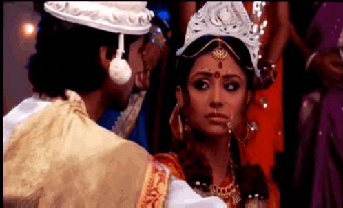 a man and a woman are standing next to each other and the woman is wearing a crown .