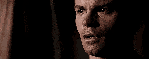 a close up of a man 's face with a serious look on his face in the dark .