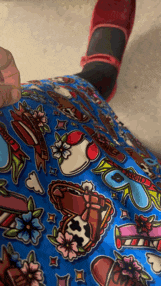 a person wearing a pair of red shoes is laying on the floor wearing a pair of blue shorts with a cow print on them